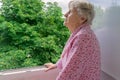 Senior woman in her home balcony looking at trees Royalty Free Stock Photo