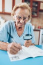 Senior woman enjoys solving a crossword puzzle Royalty Free Stock Photo