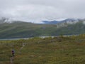 Senior woman hiker at Kungsleden hiking trail with Lapland nature with green mountains, Teusajaure lake, rock boulders, autumn Royalty Free Stock Photo