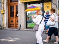Senior woman holding a colored umbrella to protect from the sun on a hot day, in Timisoara