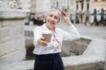 Senior woman holding cup of coffee while sitting on fountain