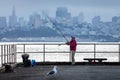 Senior woman holding fish rod on waterfront with background of San Francisco Royalty Free Stock Photo