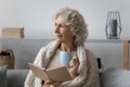 Senior woman holding paper book and hot tea. Royalty Free Stock Photo