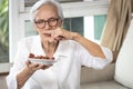 Senior woman holding plate of bad spoiled or expired food in her hand,rotten food,emitting a fetid smell or strong-smelling food, Royalty Free Stock Photo