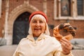 Senior woman holding prezel, traditional polish snack on the Market square in Krakow