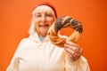 Senior woman holding prezel, traditional polish snack on the Market square in Krakow