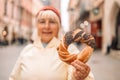 Senior woman holding prezel, traditional polish snack on the Market square in Krakow