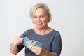 Senior Woman Holding Tarot Cards Against Gray Wall