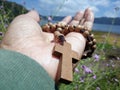 Senior woman holding wooden  rosary in hand with Jesus Christ Cross Crucifix. Christian Catholic religious symbol of faith concept Royalty Free Stock Photo