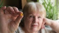 Senior woman holding yellow omega 3 gel capsule. Fish oil supplement