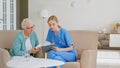 Senior woman holds bottle of pills listening to doctor advice at appointment in light office