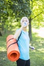 Senior woman holds fitness mat on her back in the park and preparing for exercise Royalty Free Stock Photo