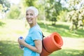 Senior woman holds fitness mat on her back in the park and preparing for exercise Royalty Free Stock Photo