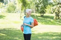 Senior woman holds fitness mat on her back in the park and preparing for exercise Royalty Free Stock Photo