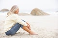 Senior Woman On Holiday Sitting On Winter Beach