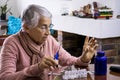 Senior woman at home arranging her prescription drugs into a weekly pill organizer