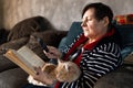 Senior Woman At Home Reading Book Using Magnifying Glass Royalty Free Stock Photo
