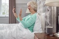 Senior Woman At Home Wearing Pyjamas In Bed Making Video Call On Mobile Phone Royalty Free Stock Photo