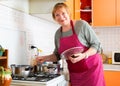 Senior woman housewife in preparing soup at home kitchen Royalty Free Stock Photo