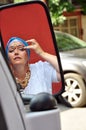 Senior woman with Indian jewlery looking at car mirrow in the s