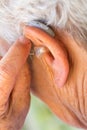 Senior woman inserting hearing aid in her ears Royalty Free Stock Photo