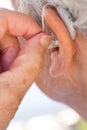 senior woman inserting hearing aid in her ears Royalty Free Stock Photo