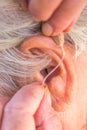 senior woman inserting hearing aid in her ears Royalty Free Stock Photo