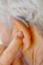senior woman inserting hearing aid in her ears Royalty Free Stock Photo