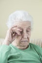 A senior woman itching her eye and face