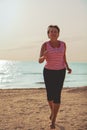 Senior woman jogging on sea beach Royalty Free Stock Photo