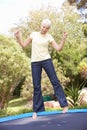 Senior Woman Jumping On Trampoline In Garden Royalty Free Stock Photo