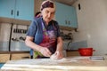 Senior woman kneading the dough in her home kitchen