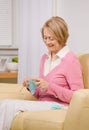 Senior woman knitting on sofa at home