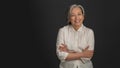 Senior woman laughing on grey background. Portrait of mature grey haired woman in white casuals looking happy on camera Royalty Free Stock Photo