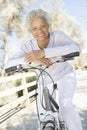 Senior Woman Leans On Handlebars Of Mountain Bike