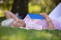 senior woman lies on green grass and reads book Royalty Free Stock Photo