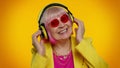 Senior woman listening music on headphones dancing disco fooling, having fun, gesticulating hands