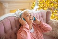 Senior woman listening music in headphones and feeling delighted