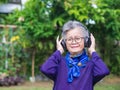 Senior woman listening music from wireless headphone Royalty Free Stock Photo