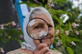 Senior woman looking through magnifying glass. Focus on magnyfiying glass. Royalty Free Stock Photo