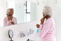 Senior Woman Looking At Reflection In Bathroom Mirror Brushing Hair Royalty Free Stock Photo