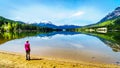 Senior woman looking at the Reflection of the Rocky Mountains range on the smooth water surface of Yellowhead Lake Royalty Free Stock Photo
