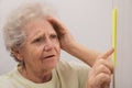 Senior woman looking at reminder note indoors. Age-related memory impairment