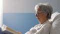 Senior woman lying in bed at the hospital and reading