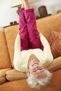 Senior Woman Lying Upside Down On Sofa At Home Royalty Free Stock Photo