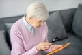 Senior woman with magnifier reading something on a tablet