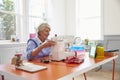 Senior Woman Making Clothes Using Sewing Machine At Home Royalty Free Stock Photo