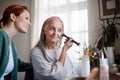 Senior woman making make up herself at home.