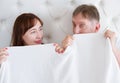 Senior Woman and man in bed. Middle age couple lying in bedroom and hiding under template blank white blanket. Copy space Royalty Free Stock Photo