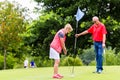 Senior woman and man playing golf putting on green Royalty Free Stock Photo